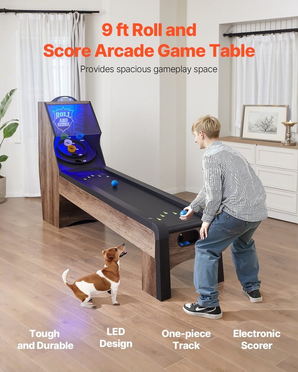 Dječak kotrlja plavu lopticu po stazi skee ball stola u dnevnom boravku, uz njega pas