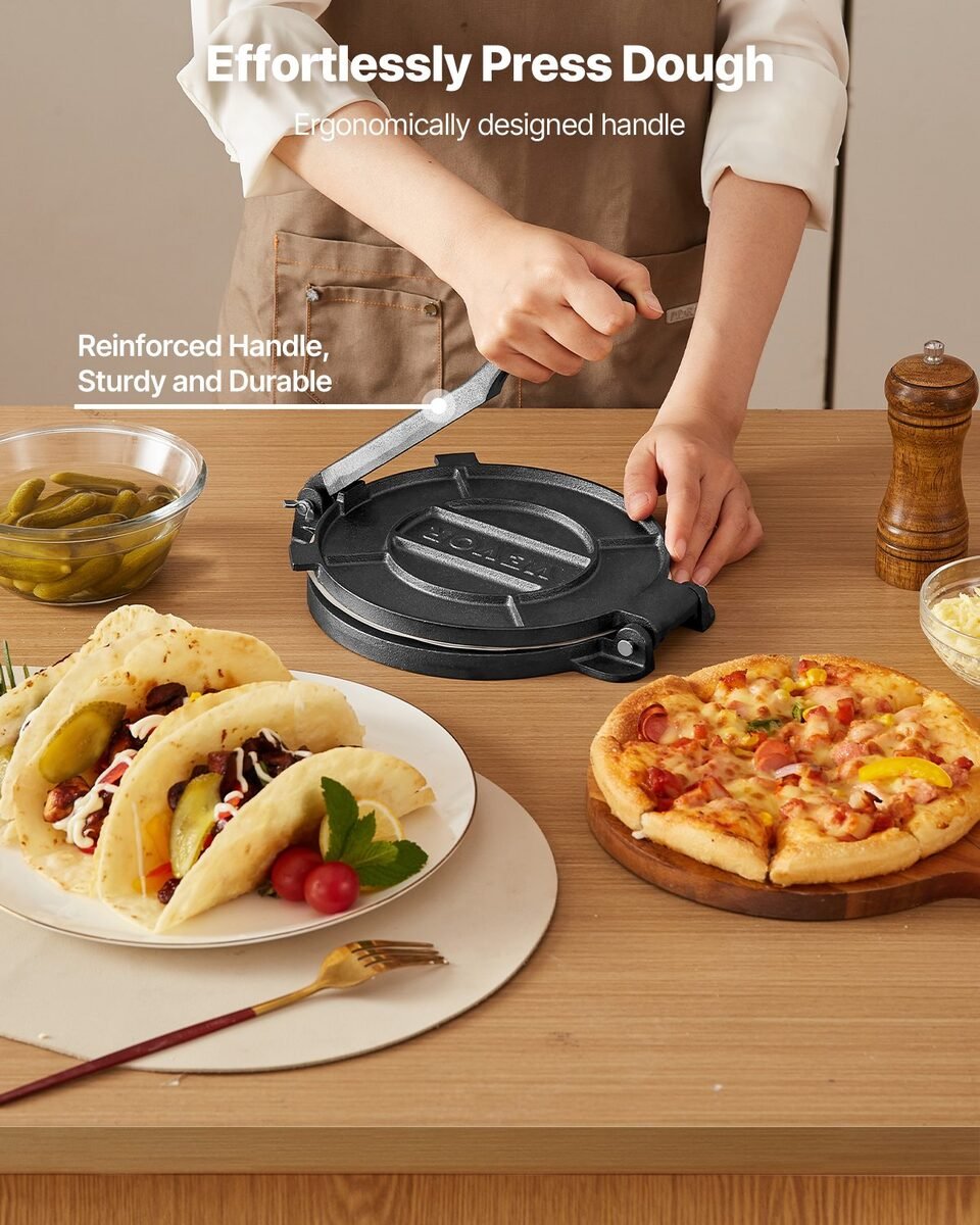 Kuharica pritišće prešu za tortilje, ispred su punjeni tacosi i pizza